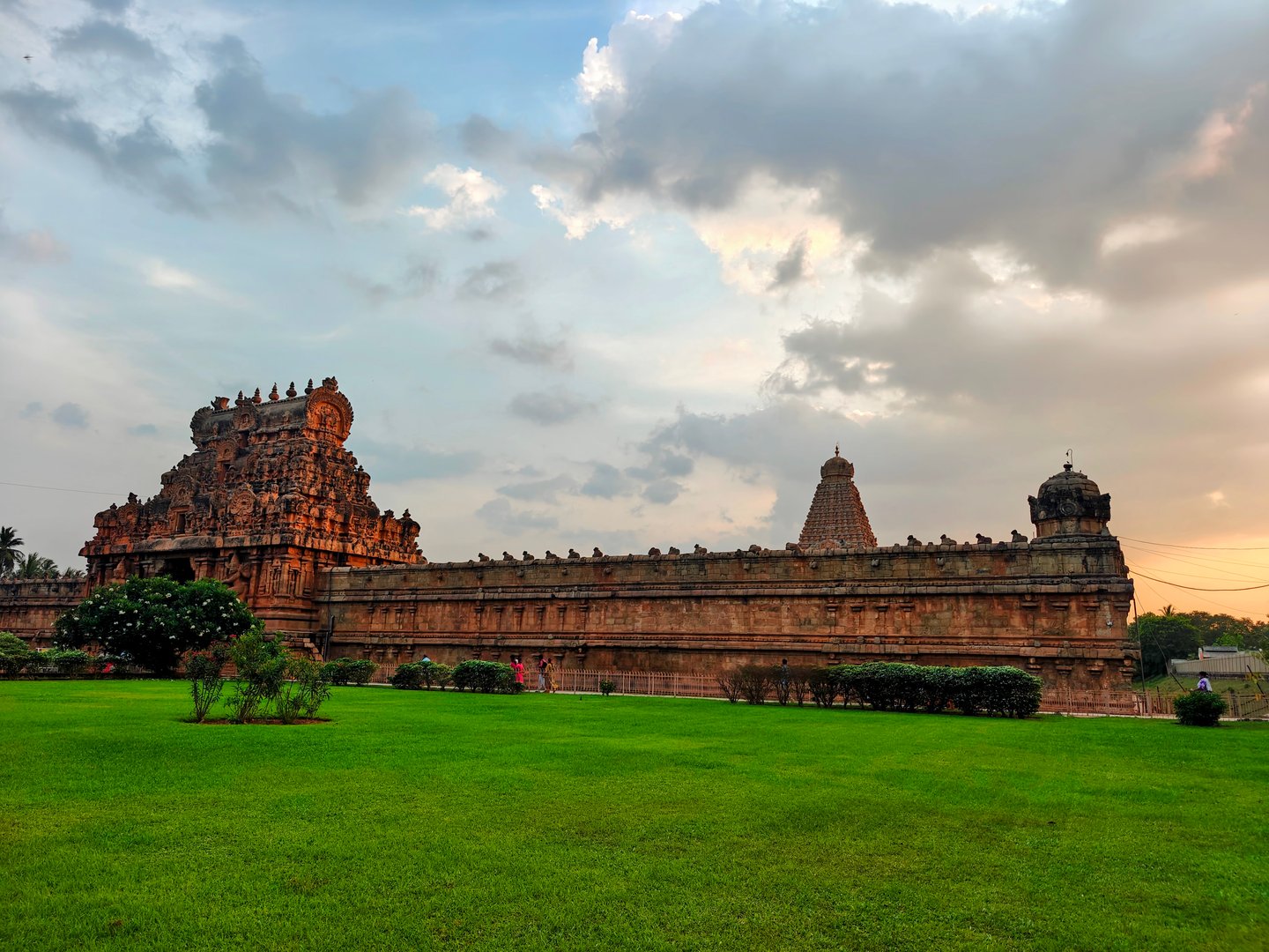 Brihadisvara Temple complex exterior at sunset — the Nandi shrine and outer walls with lush gardens, Thanjavur