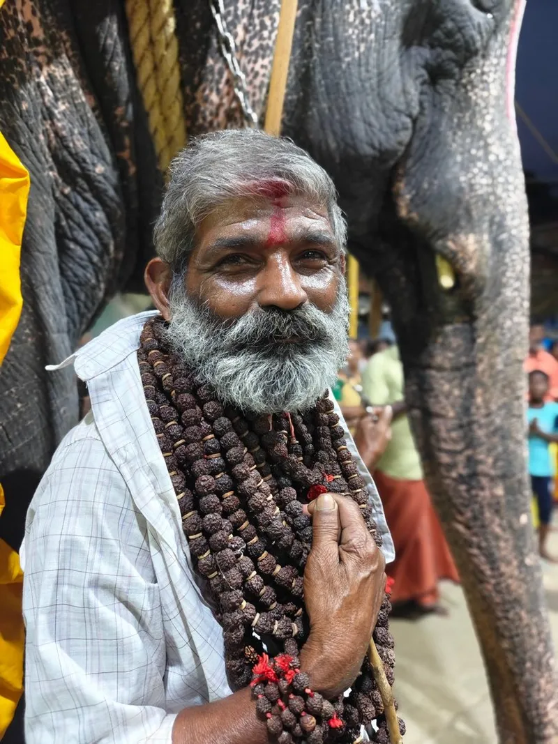 The mahoot — the elephant's dedicated caretaker for over two decades — stands with hands folded in greeting beside the temple elephant he has served since childhood