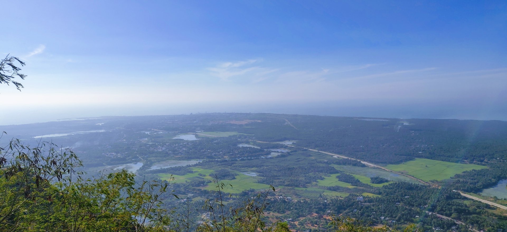 Panoramic view from the summit of Marunthuvazh Malai looking over Kanyakumari district — the Arabian Sea, Bay of Bengal, and Indian Ocean visible on the horizon — Photo: Sabin, sabinv.com